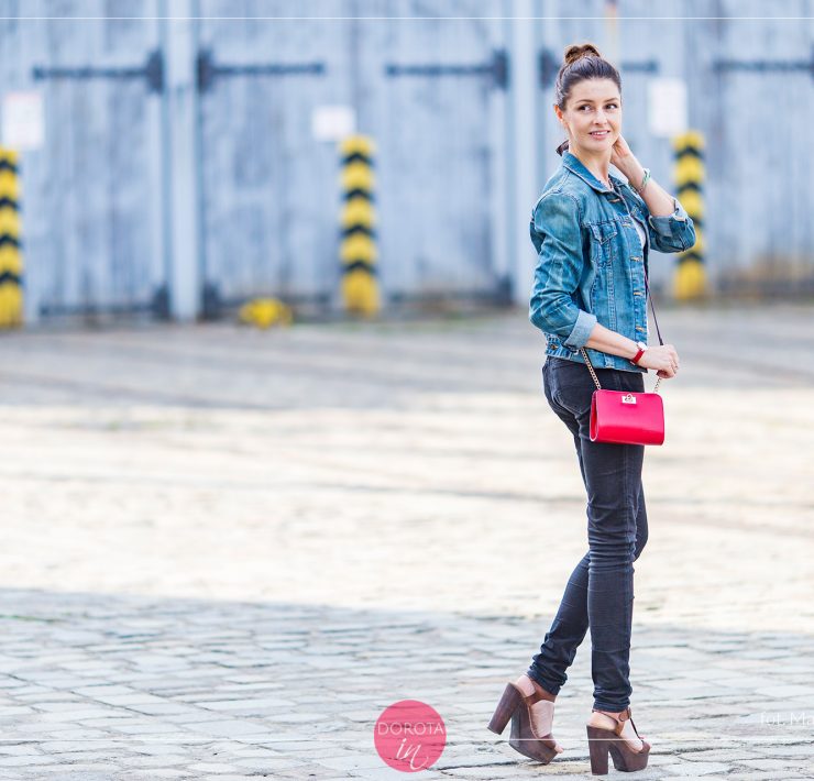 Dzinsowa kurtka, czarne spodnie, wysokie sandały i czerwona torebka