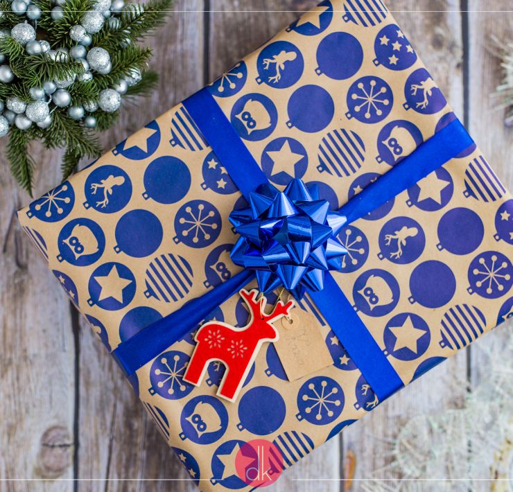 Prezent spakowany w szary papier z granatową wstążką i niebieskim wzorem